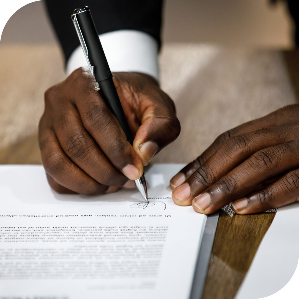 close up the hands of a Black man signing a legal document