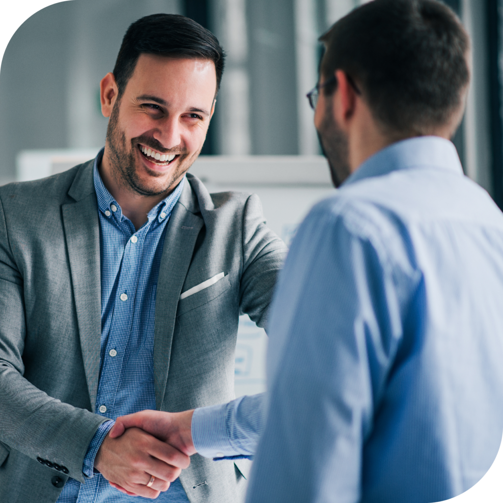 Two men in business attire smiling and shaking hands, closing a PBM renewal deal. 