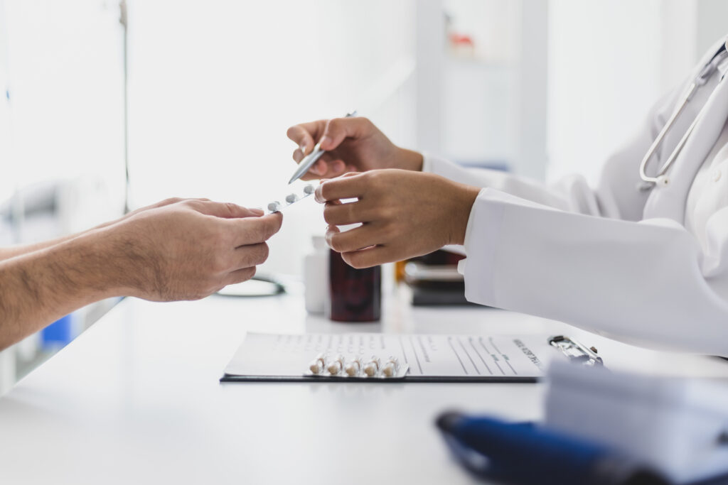 close up on hands of doctor handing specialty medication to patient, consulting with member about specialty medication
