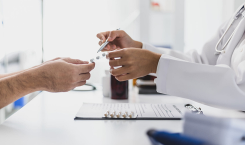 close up on hands of doctor handing specialty medication to patient, consulting with member about specialty medication