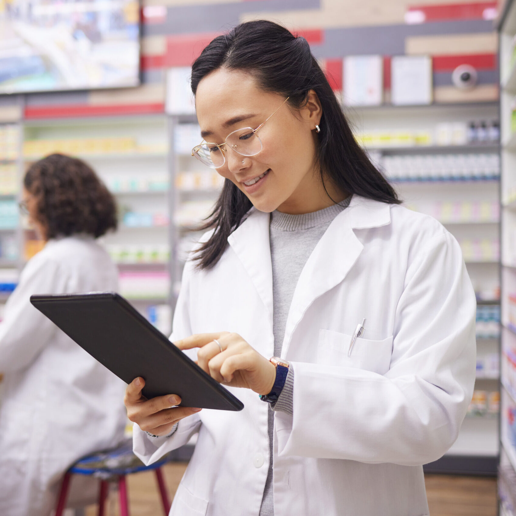 A pharmacist in a pharmacy checking pharmacy benefit manager plan details